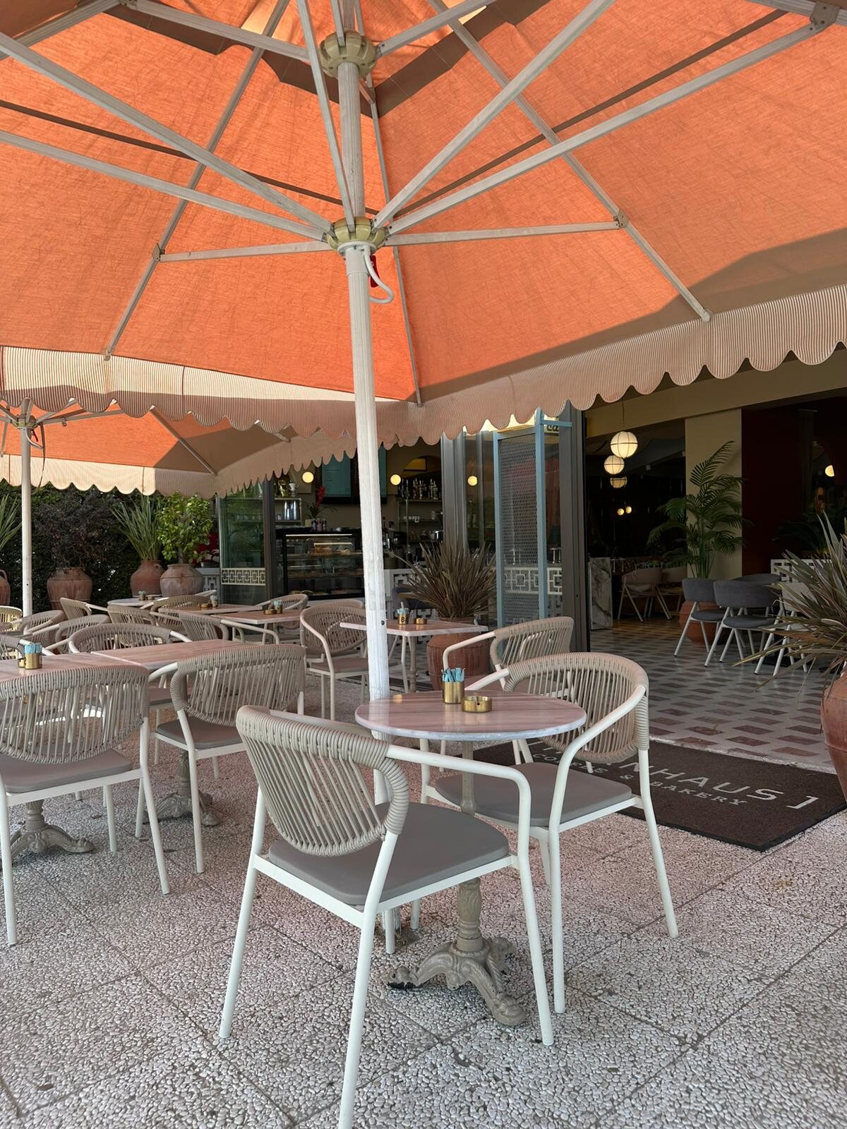 HÖRNHAUS terasında turuncu şemsiye altında dış mekan oturma alanı.